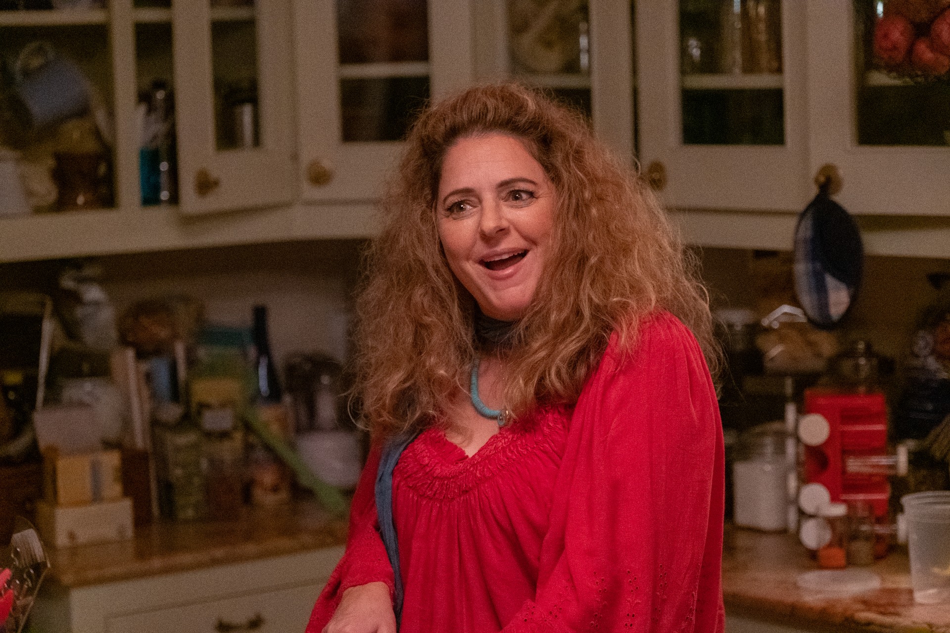 Annie Mumolo lächelt in einer Küche in einer Szene aus Confess, Fletch.
