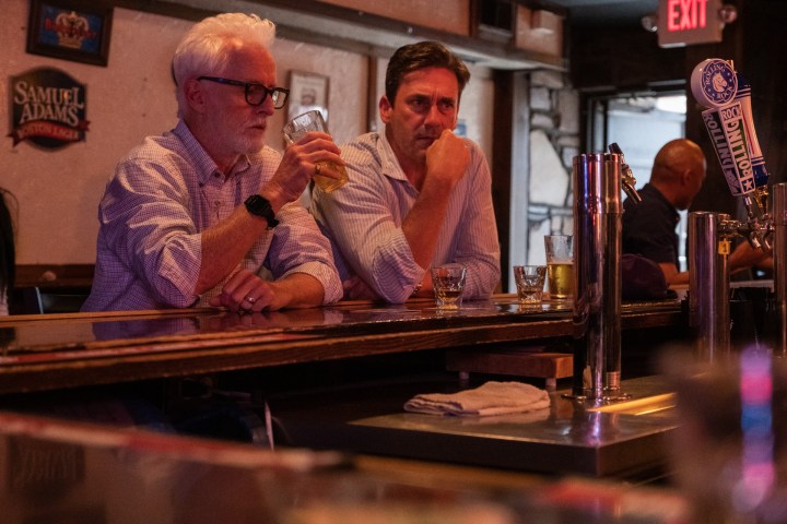 John Slattery and Jon Hamm sit at a bar in a scene from Confess, Fletch.