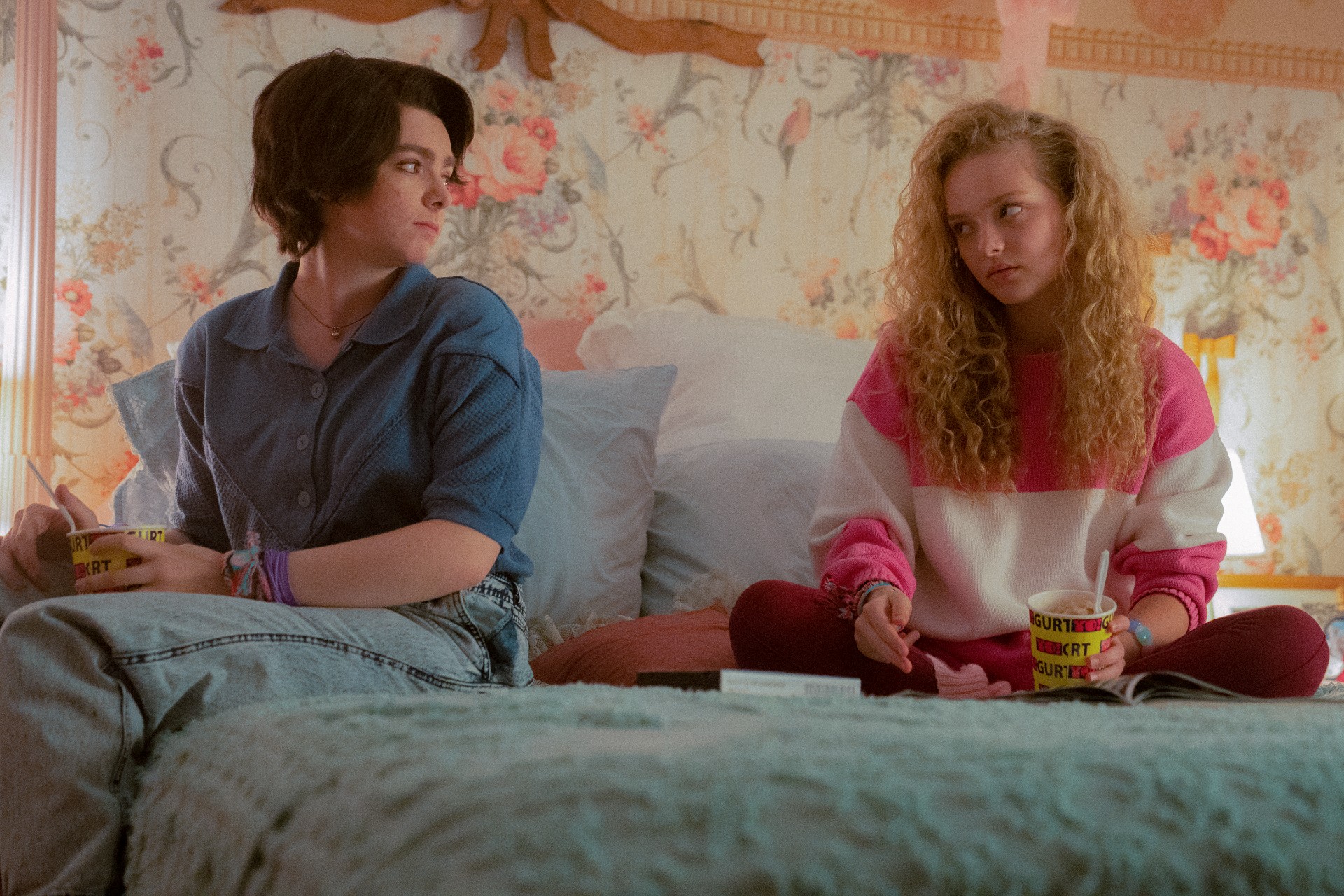 Elsie Fisher e Amiah Miller estão sentadas em uma cama em uma cena de O Exorcismo do Meu Melhor Amigo.