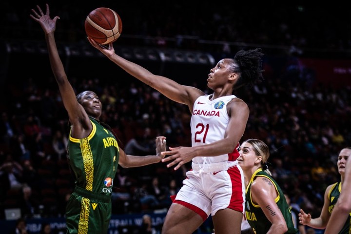 Two female basketball players in the middle of a play.