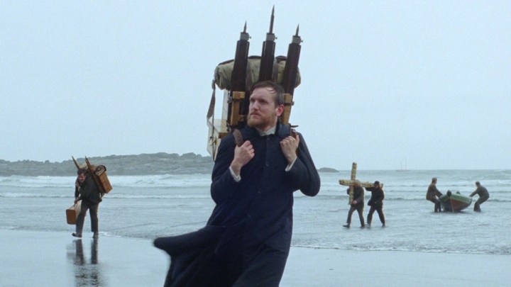 Un prete cammina su una spiaggia a Godland.