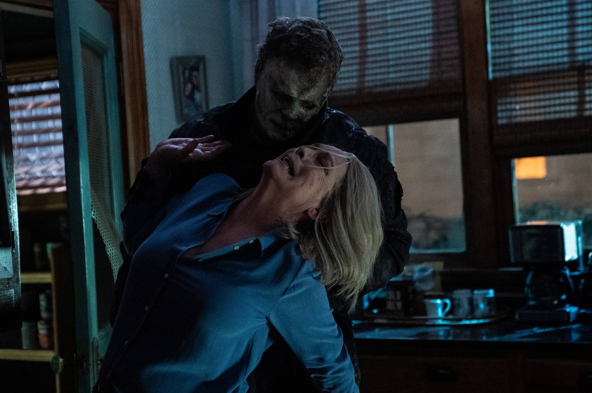 Michael Myers segura Lauri Strode de Jamie Lee Curtis pelo pescoço em uma cena de Halloween Ends.