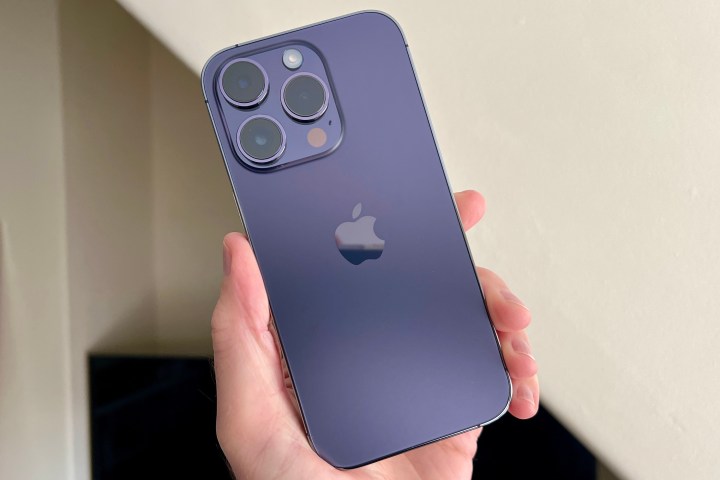 iPhone 14 Pro in Deep Purple, held in a mans hand.