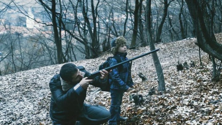Um homem aponta uma arma com um menino ao lado dele na RMN