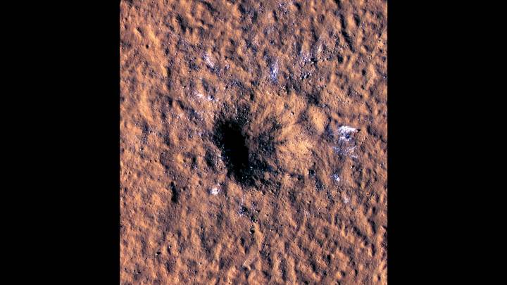 Boulder-size blocks of water ice can be seen around the rim of an impact crater on Mars.