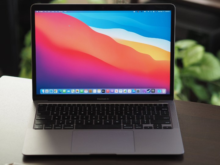 An Apple M1 MacBook Air is open on a desk with plants in the background.