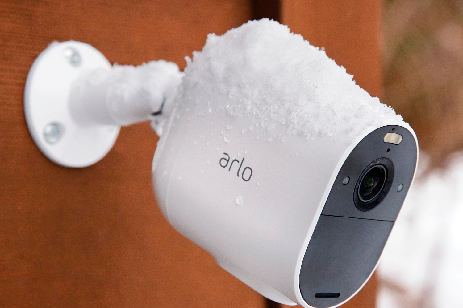 Câmera de segurança Arlo ao lado da casa com neve.