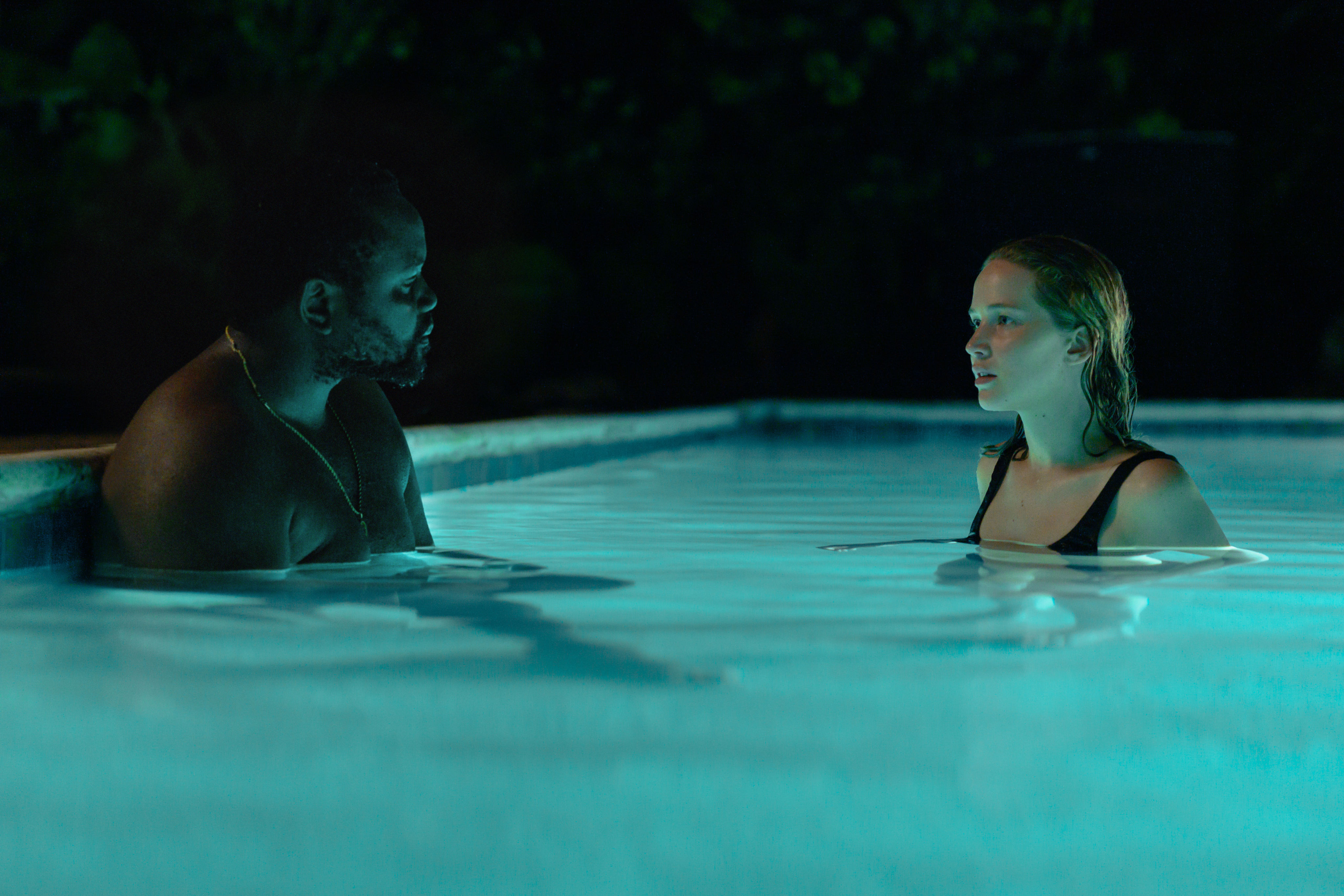 Brian Tyree Henry e Jennifer Lawrence se olham em uma piscina em Causeway.