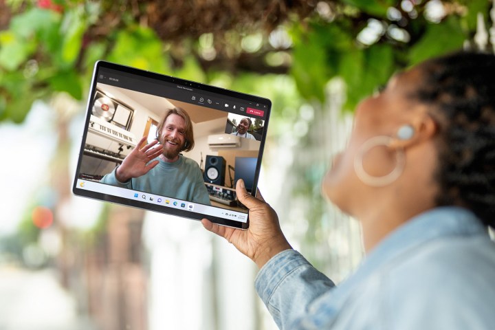 A person holds a Microsoft Surface Pro 9 during a video call.
