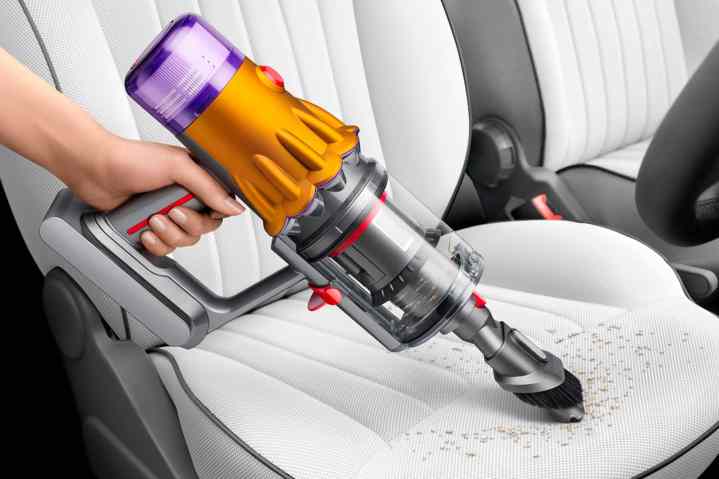 Dyson V12 Detect cordless vacuum being used to clean car interior.