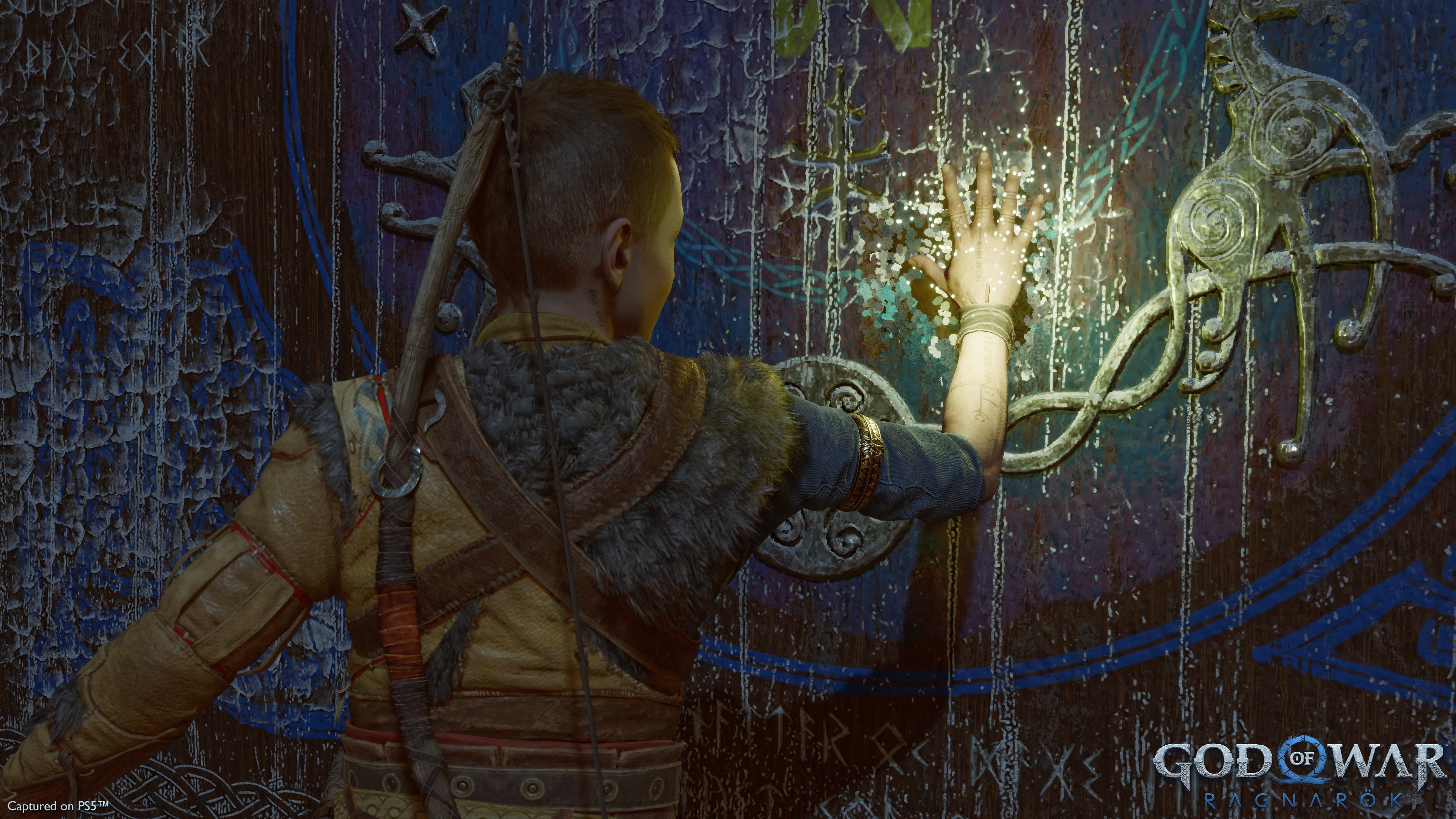 God of War Ragnarok Atreus bir duvar resmine dokunuyor.