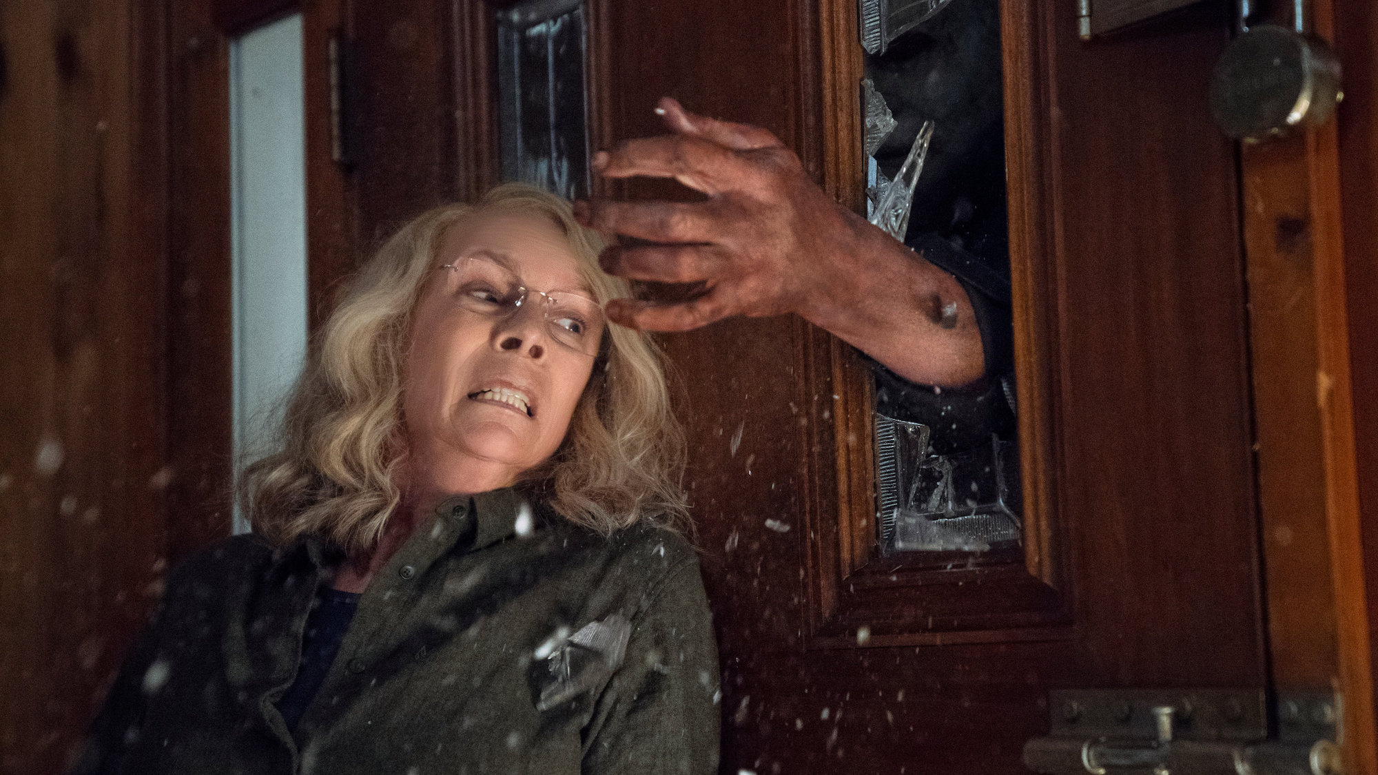 Michael Myers quebra a mão em uma porta de vidro no Halloween (2018)