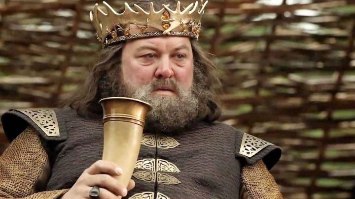 Robert Baratheon sostiene una taza y parece molesto en Game of Thrones.