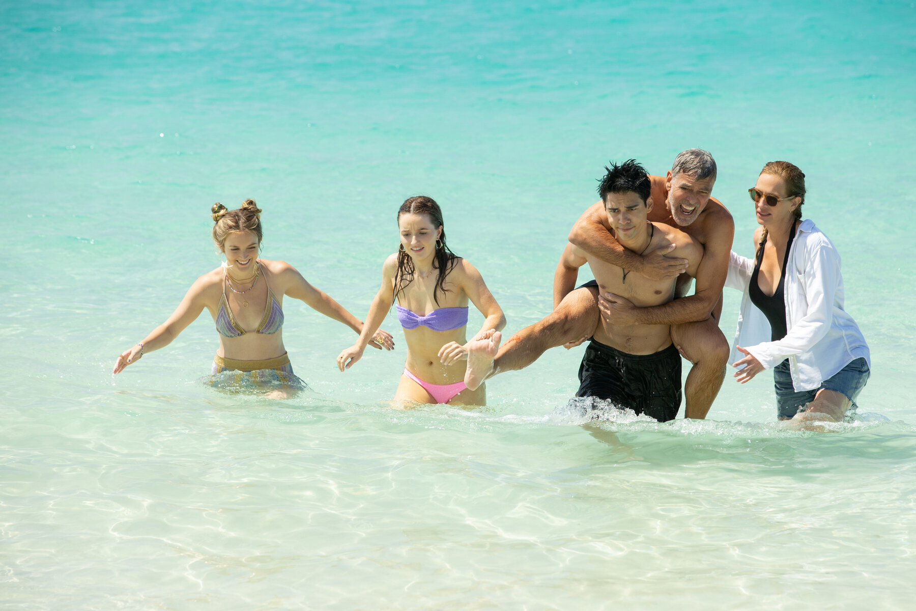Maxime Bouttier carries George Clooney out of the ocean in Ticket to Paradise.