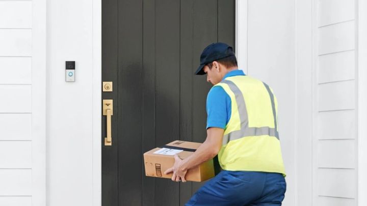 A person delivering a package to a door with Ring Video Doorbell 4 installed.