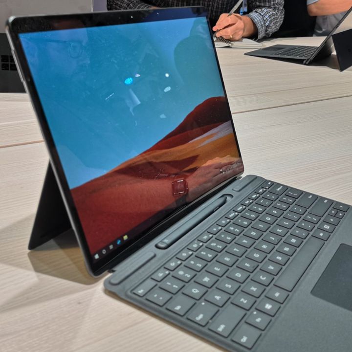 A Microsoft Surface Pro X stands upright with a keyboard attachment on a table.