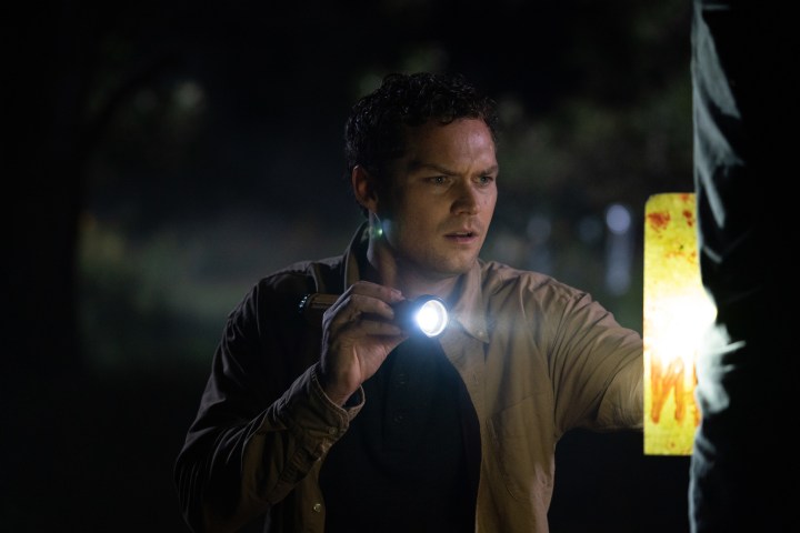 Finn Jones segura uma lanterna em uma cena de The Vistor.