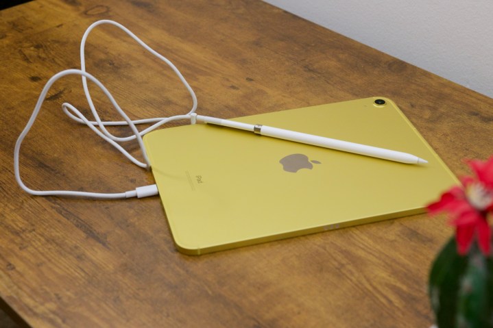 O iPad (2022) com um Apple Pencil conectado usando um cabo e adaptador USB-C.