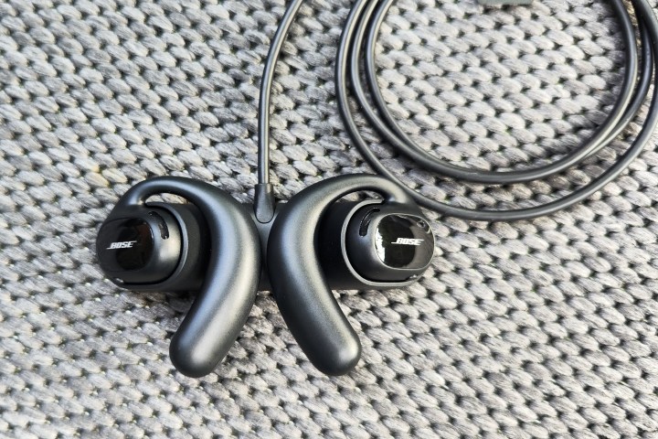 Bose Sport Open Earbuds sitting in charging cradle.
