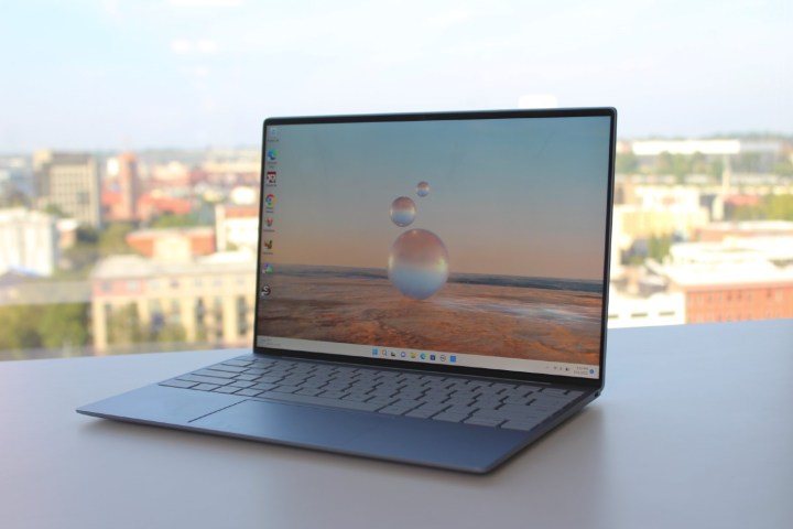 The Dell XPS 13 open on a table in front of a window.