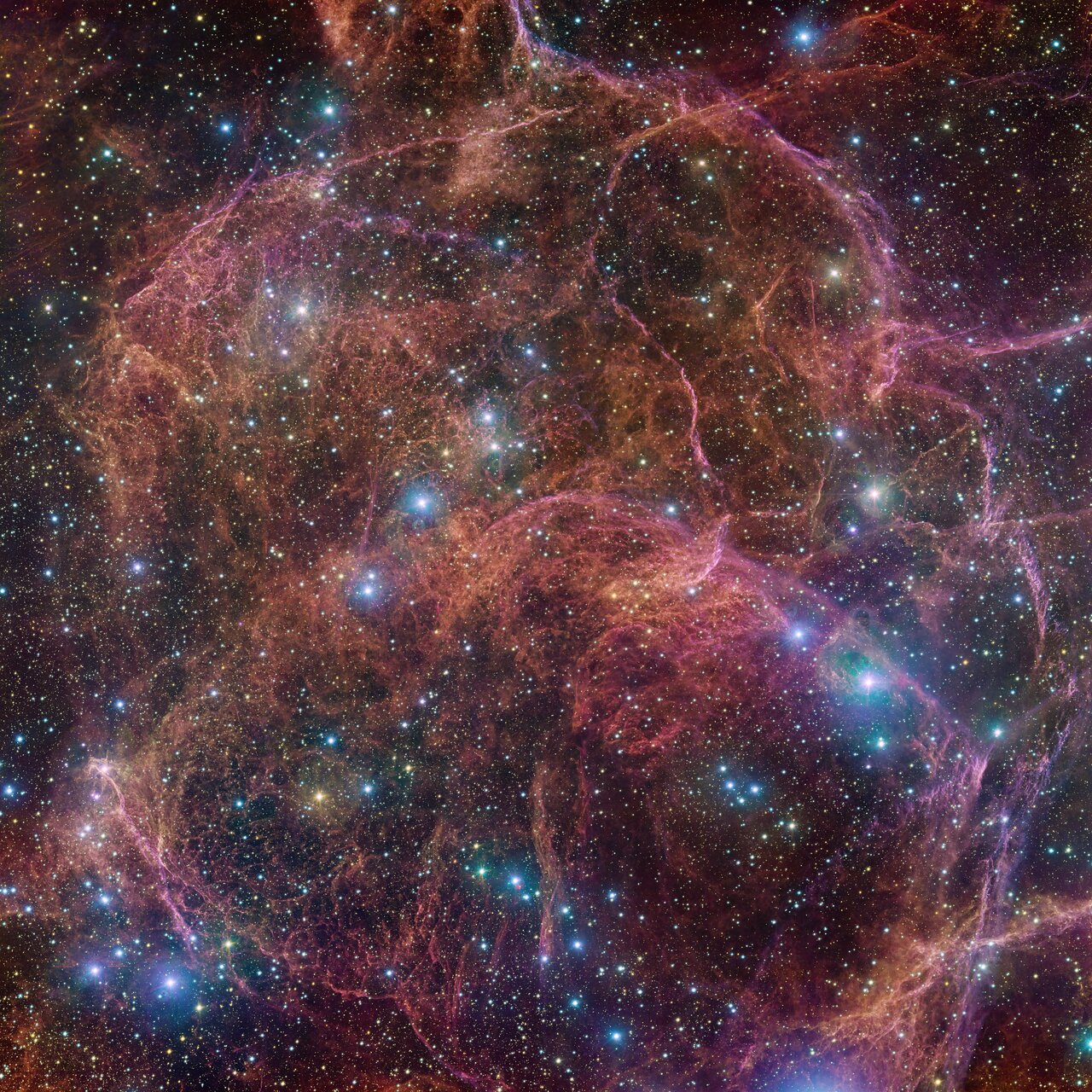 Dieses Bild zeigt einen spektakulären Blick auf die orangefarbenen und rosafarbenen Wolken, die das bilden, was nach dem explosiven Tod eines massereichen Sterns übrig bleibt – der Vela-Supernova-Überrest.  Dieses detaillierte Bild besteht aus 554 Millionen Pixeln und ist ein kombiniertes Mosaikbild von Beobachtungen, die mit der 268-Millionen-Pixel-OmegaCAM-Kamera am VLT Survey Telescope aufgenommen wurden, das am Paranal-Observatorium der ESO untergebracht ist.  OmegaCAM kann Bilder durch mehrere Filter aufnehmen, die das Teleskop jeweils das emittierte Licht in einer bestimmten Farbe sehen lassen.  Um dieses Bild aufzunehmen, wurden vier Filter verwendet, die hier durch eine Kombination aus Magenta, Blau, Grün und Rot dargestellt werden.  Das Ergebnis ist eine äußerst detaillierte und atemberaubende Ansicht sowohl der gasförmigen Filamente im Überrest als auch der hellblauen Sterne im Vordergrund, die dem Bild Glanz verleihen.