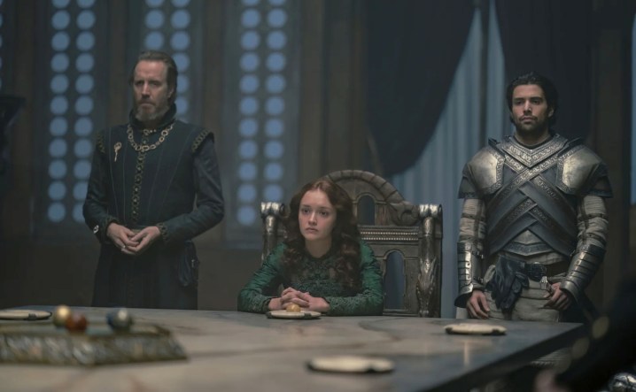 A woman and two men sit at a table in House of the Dragon.