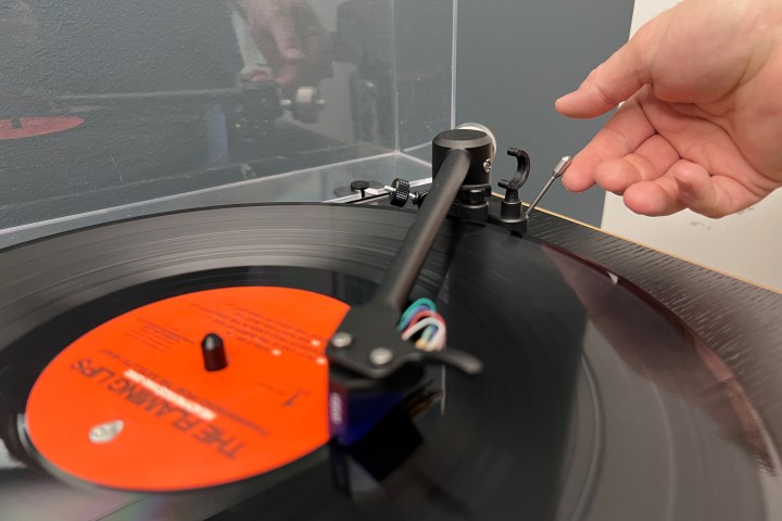 Raising the cue lever on a turntable to stop a record.