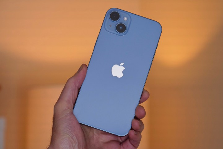 The iPhone 14 Plus held in a man's hand.