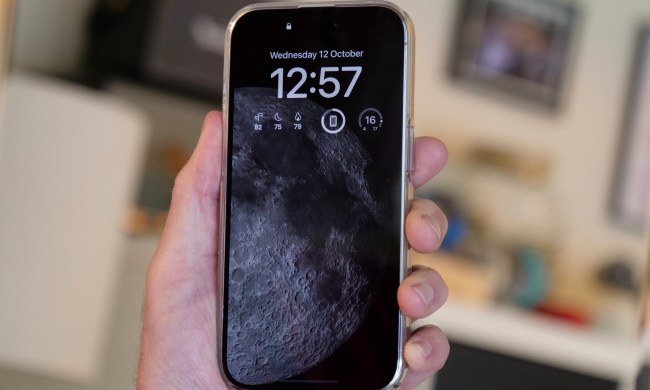 iPhone 14 Pro showing the Moon always-on screen, held in a man's hand.