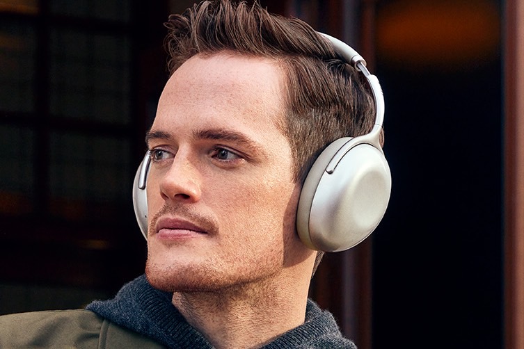Hombre con auriculares inalámbricos KEF Mu7 con cancelación de ruido.