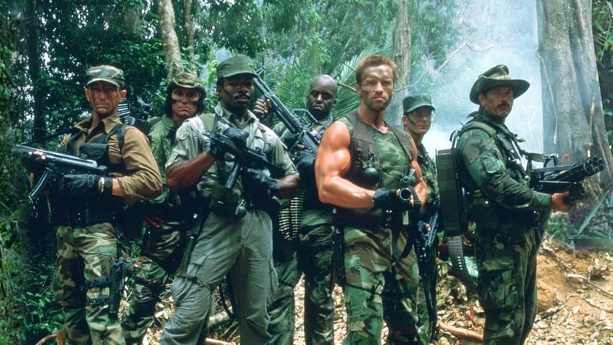 O elenco de Predator posa com suas armas na selva.