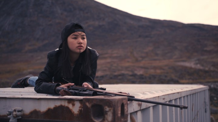 Tasiana Shirley sits on top of a shipping container with a rifle in a scene from Slash/Back.