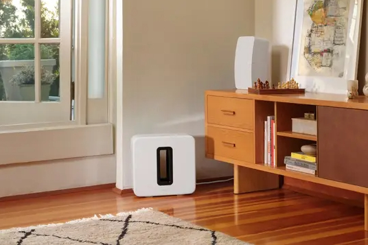 A white Sonos Sub (3rd Gen) in a living room setting.