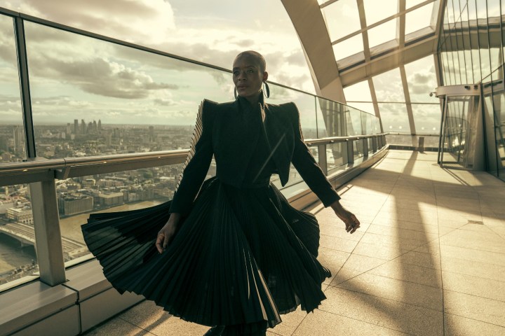 T'Nia Miller walks across a balcony in a black dress in a scene from The Peripheral.