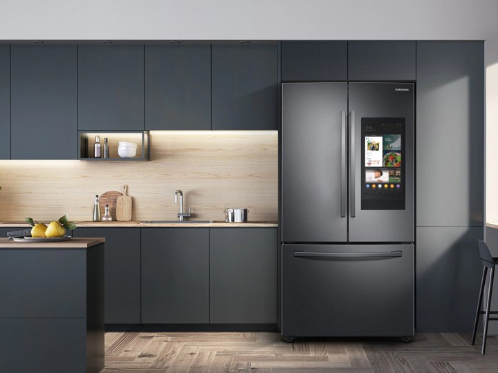 28 cu. ft. Samsung 3-Door French Door Refrigerator with Family Hub in a kitchen with dark gray cabinets and a wooden floor
