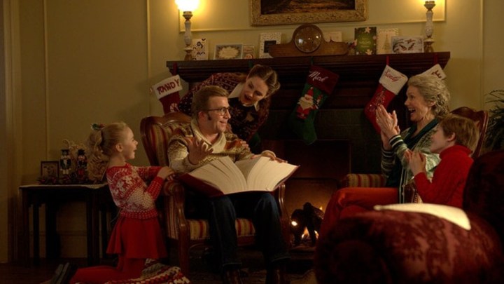 A family sits around a fire and reads a book in a scene from A Christmas Story Christmas.