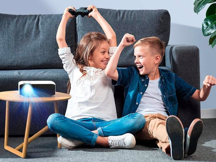 A boy and girl play video games on the Apeman LC350 Full HD projector.