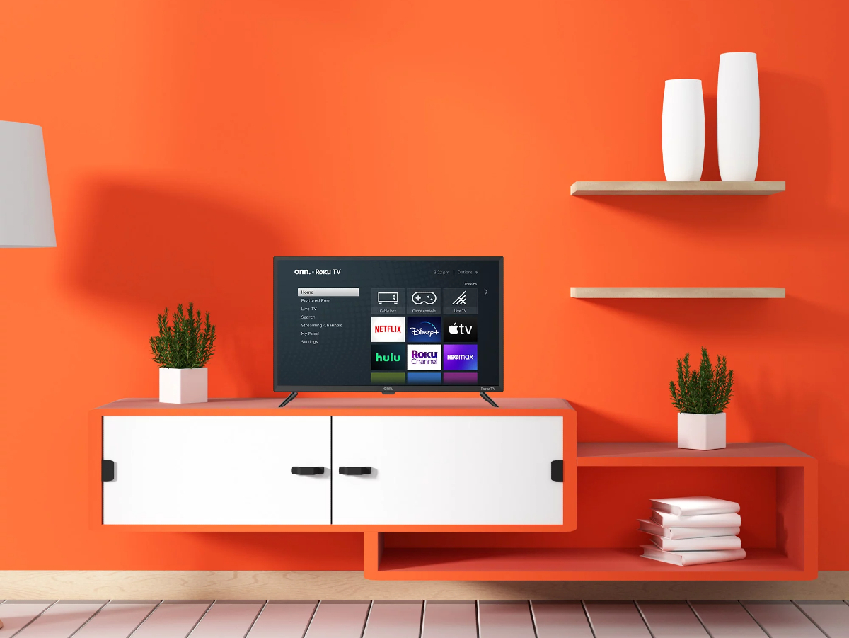 An onn 32-inch class HD (720P) LED Roku Smart TV in a sparsely furnished room with orange walls.
