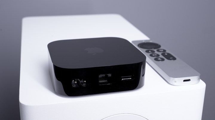 Rear view of Apple TV 4K showing Gigabit Ethernet port, HDMI port, and power port, with Siri remote in the background.