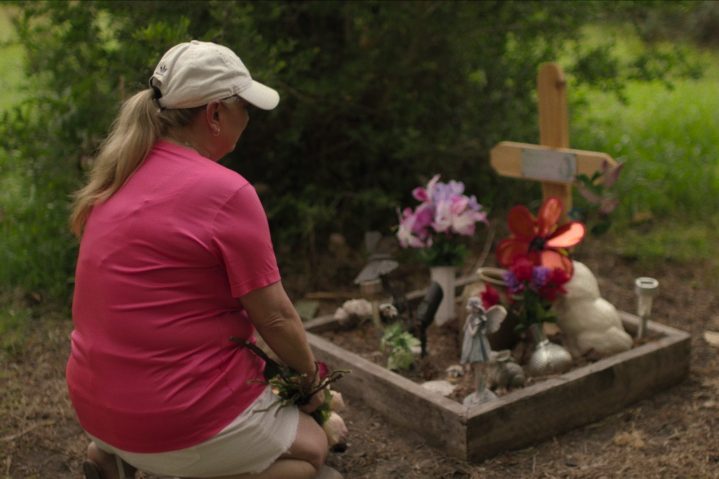 Una mujer se arrodilla ante una cruz en Crime Scene: The Texas Killing Fields.
