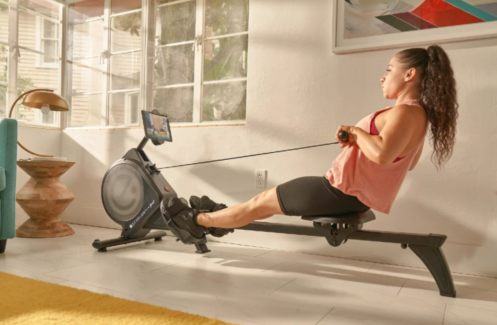 Woman exercising with the Echelon smart rower in a sunny room.