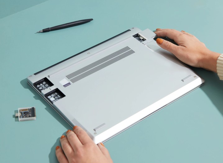 Un laptop Framework capovolto con due mani che lo tengono e le porte USB svitate