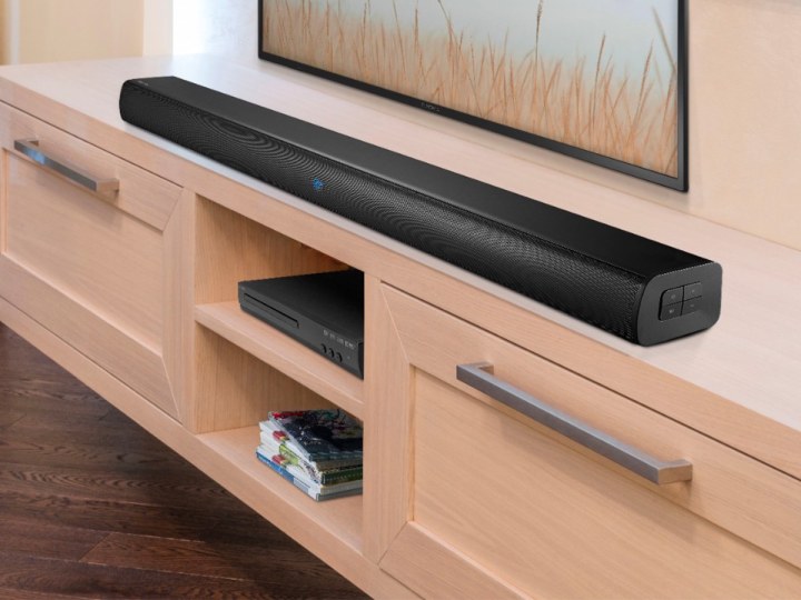 La barra de sonido Insignia de 2 canales se encuentra en un gabinete de entretenimiento debajo de un televisor.