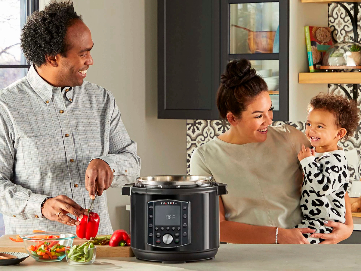 Panela de pressão elétrica Instant Pot de 6 quartos com a família em uma cozinha e o pai cortando pimentões vermelhos.