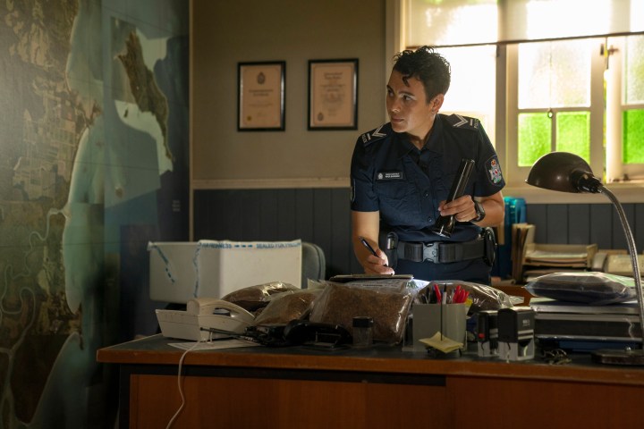 Un flic utilise une lampe torche à son bureau dans une scène d'Irreverent.