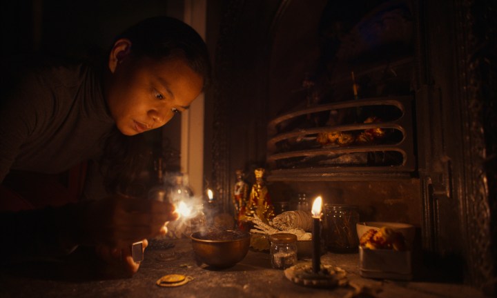 Uma mulher acende uma vela em uma cena de Nocebo.