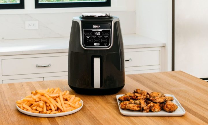 Ninja Air Fryer Max XL on a kitchen table with wings and fries.