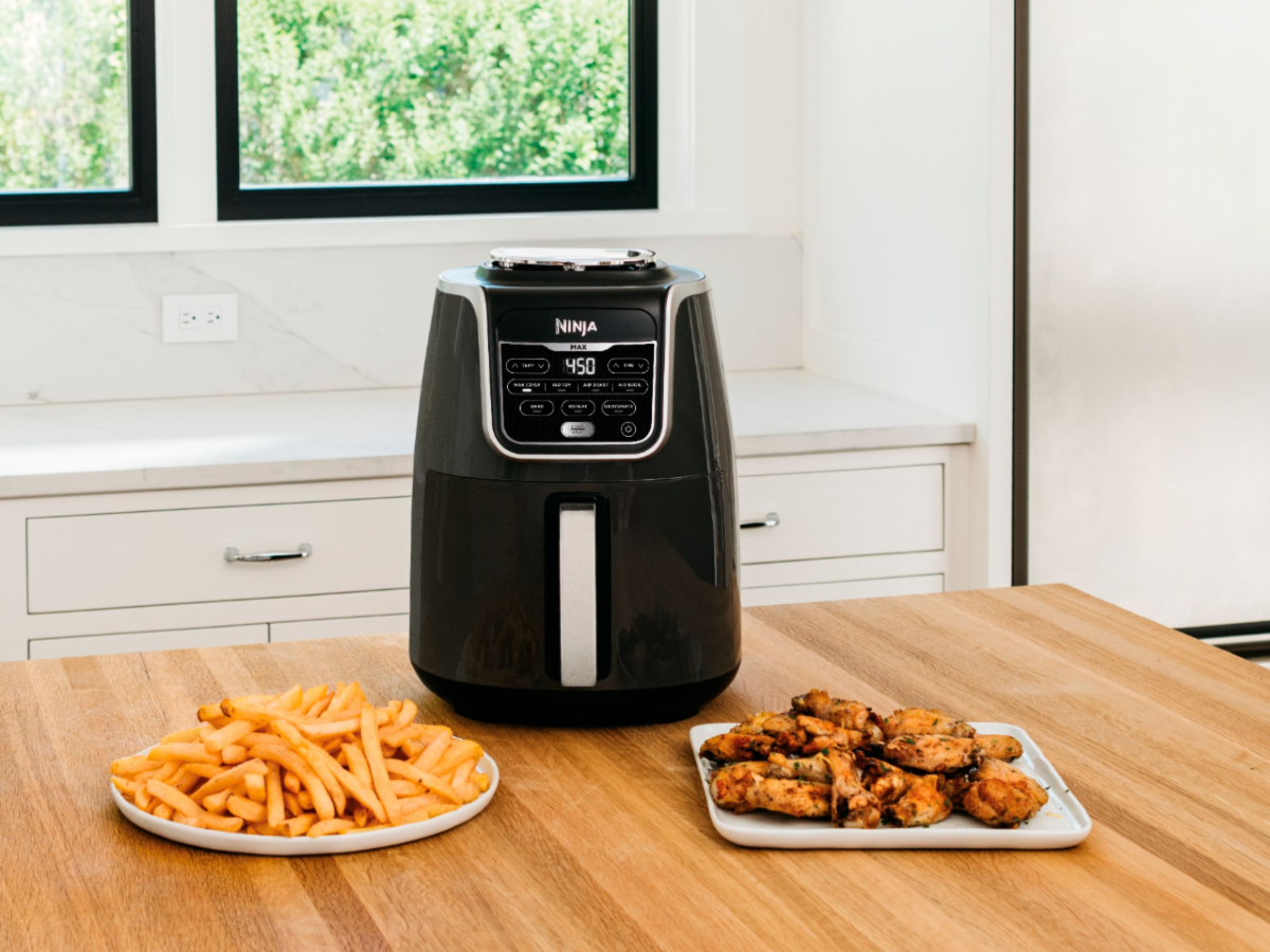 Ninja Air Fryer Max XL on a kitchen table with wings and fries.