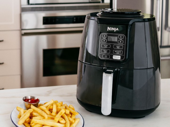 Ninja Air Fryer with a plate of fries sittin on a gray countertop.