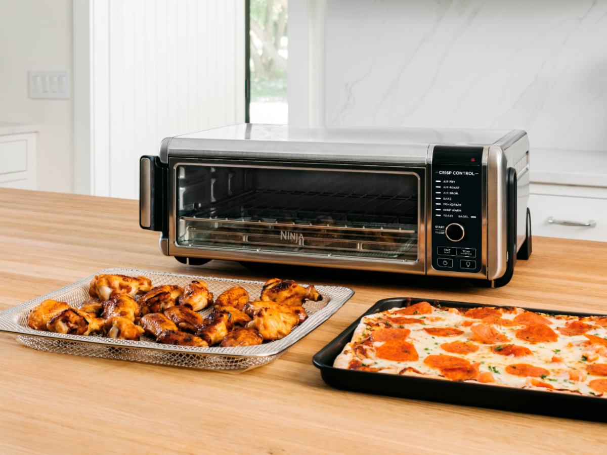 Ninja Foodi 8-in-1 Digital Air Fry Oven em um balcão de cozinha com pizza e asas.
